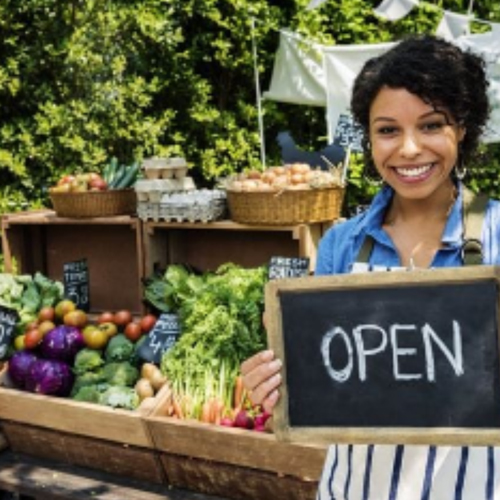 lady-holding-open-sign-infront-of-her-stand